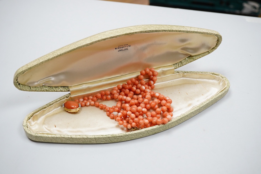A coral necklace, composed of three strands of coral beads measuring approximately 5.1-6.6mm diameter, to a gold clasp set with a coral cabochon and brilliant-cut diamonds, mounted in gold, length 45.5cm, stamped 14K, ca